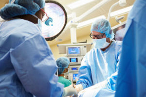 Nurses and doctors in scrubs work on a surgery.