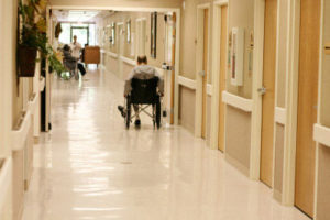 A man in a wheel chair inside a nursing home hallway