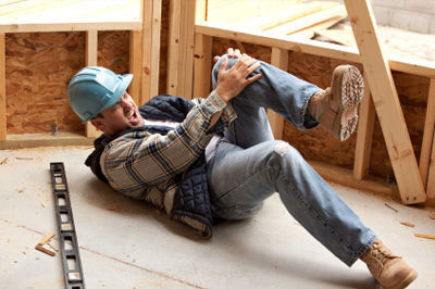 A construction worker lays on the ground in obvious pain